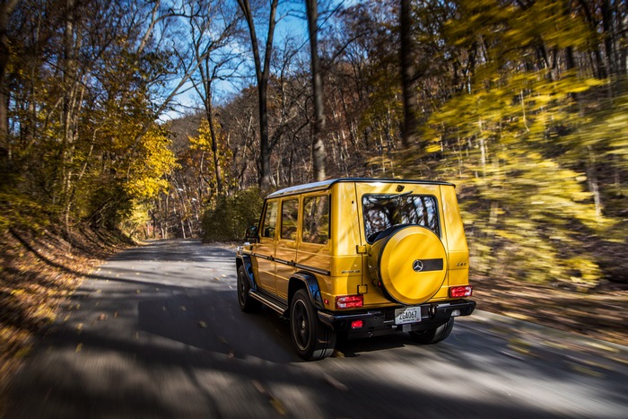 Yellow Mercedes-AMG G-Class driving on a road in autumn