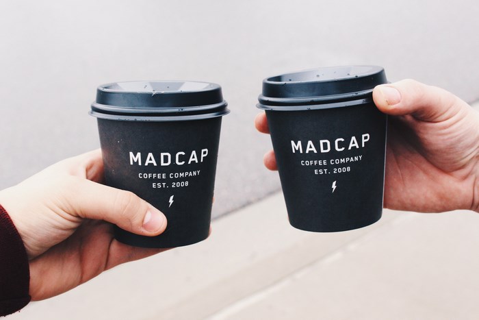 Madcap Coffee Company cups held by two hands