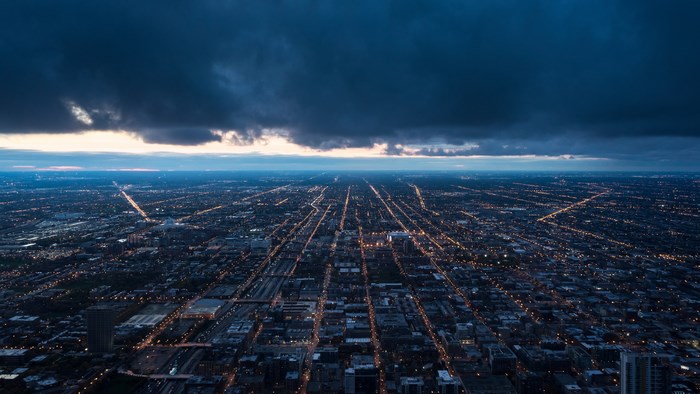 Aerial view of city lights at dusk with stormy clouds