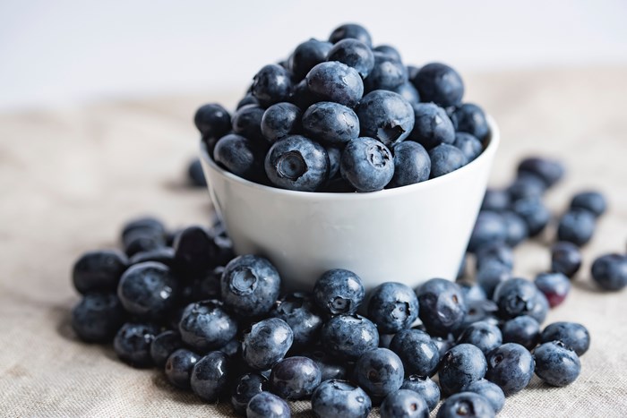 A white bowl overflowing with fresh blueberries