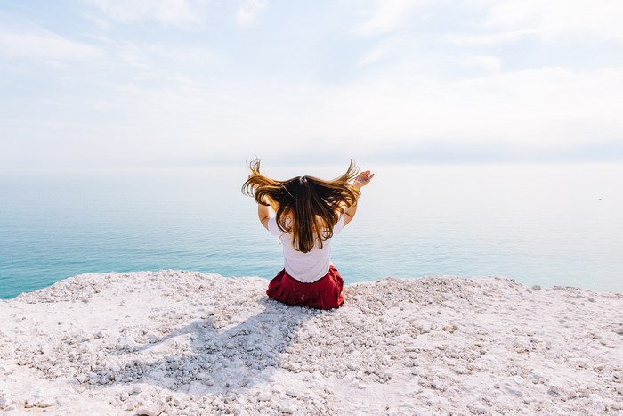 Woman sitting on a cliff edge overlooking the sea