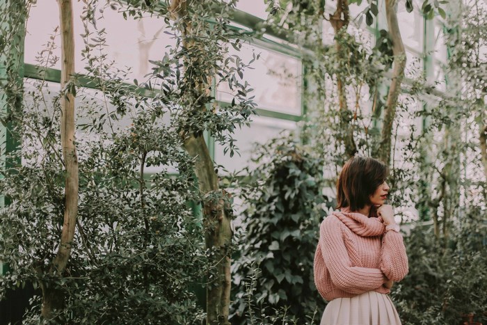 Woman in pink sweater in a greenhouse