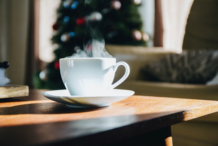 Steaming cup of coffee on a table with Christmas tree
