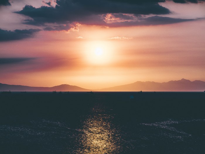 Sunset over the ocean with islands on the horizon
