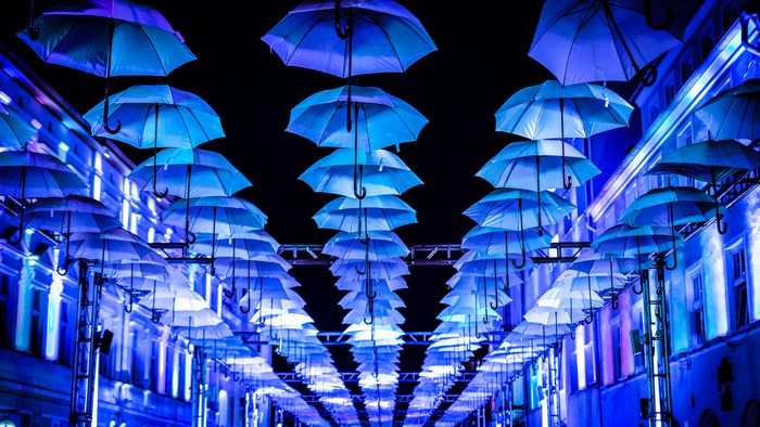 Blue umbrellas illuminated at night above a street