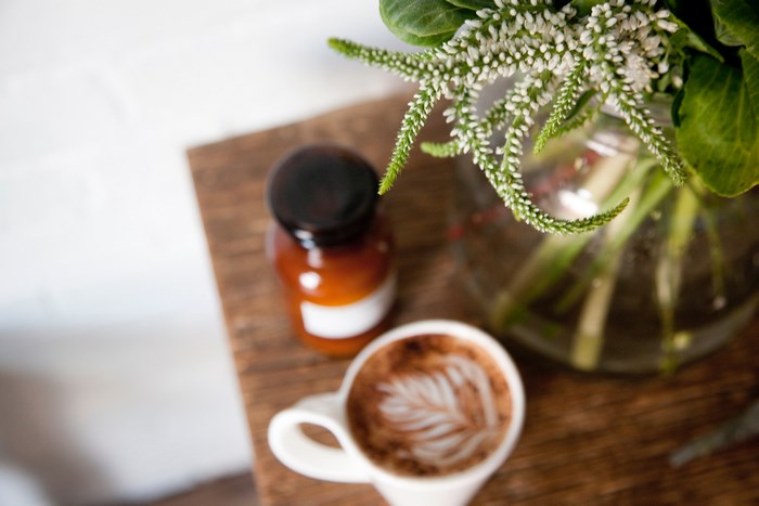 Latte art coffee cup with flowers and a bottle