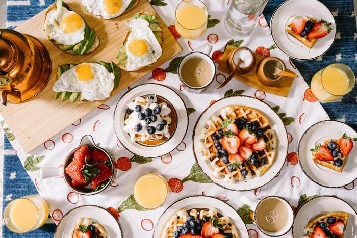 Breakfast spread with waffles, eggs, avocado, and fruits