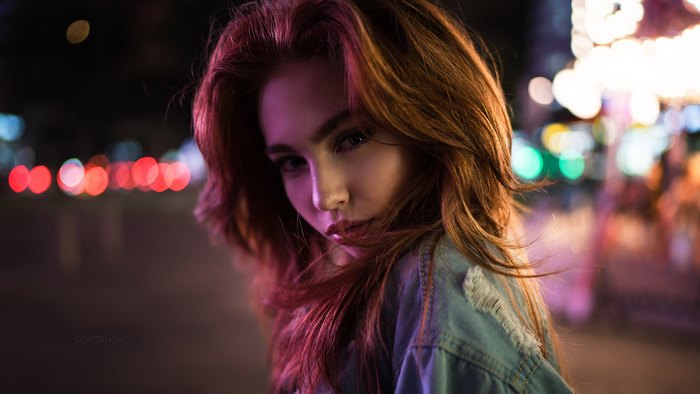 Girl in denim jacket at night with city lights