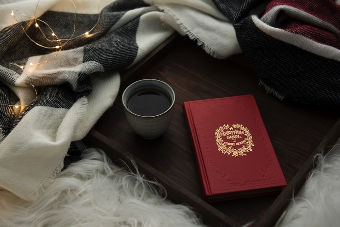A Christmas Carol book with a blanket and tea