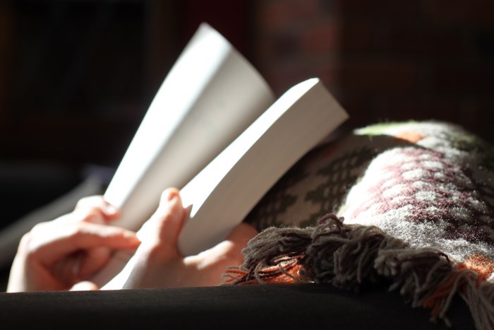 Person reading a book under natural light