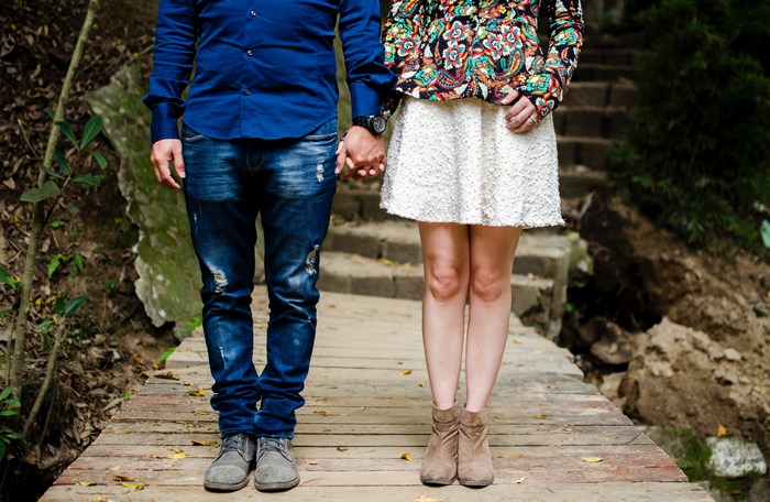 Couple holding hands on a wooden path