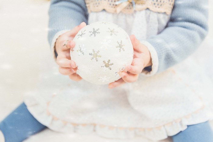 Child holding a snowflake Christmas ornament