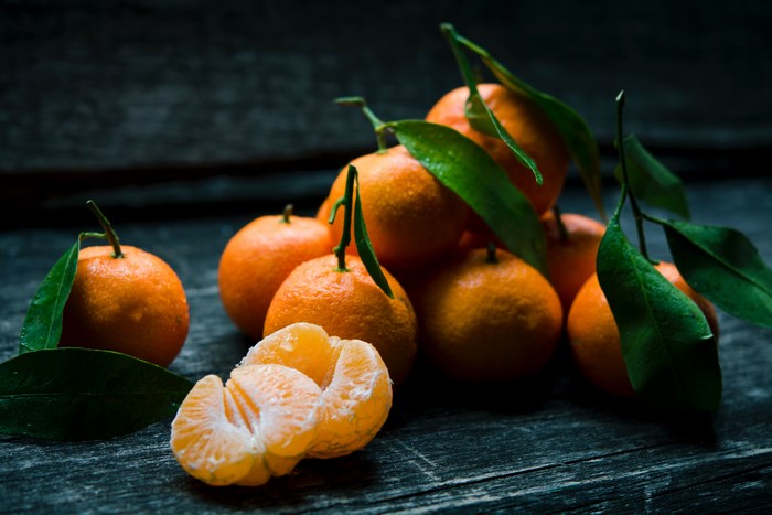 Tangerines with leaves on a dark wooden surface