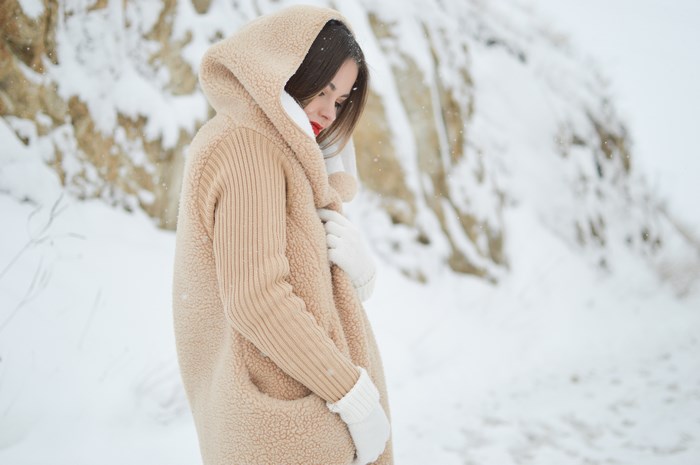 Woman in a tan hooded coat in the snow