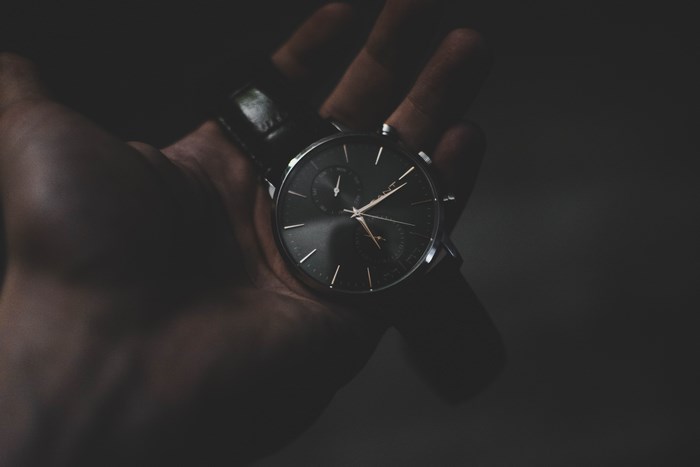 Man holding a dark analog watch with gold accents