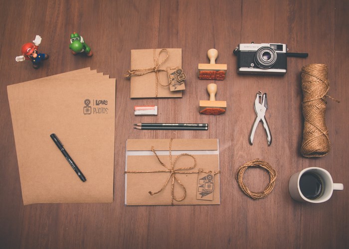 Flat lay of stationery, camera, and coffee on a wooden desk