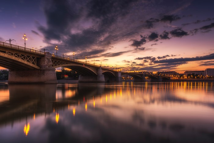 Bridge over river at twilight with city lights reflection