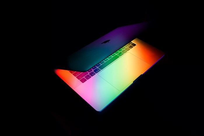 MacBook illuminated by rainbow light