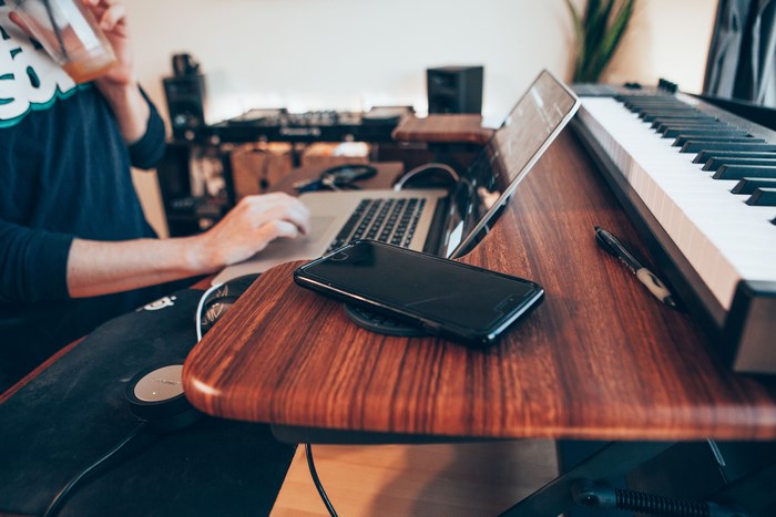 Person working on laptop with piano and phone