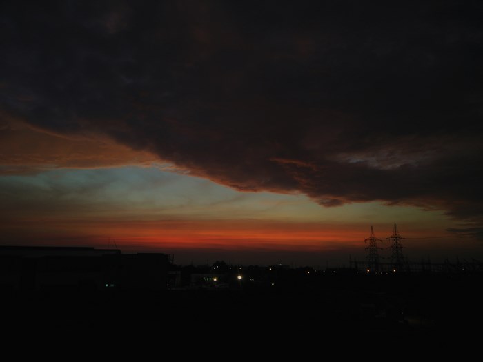 Dark cloudy sky over industrial silhouette at sunset