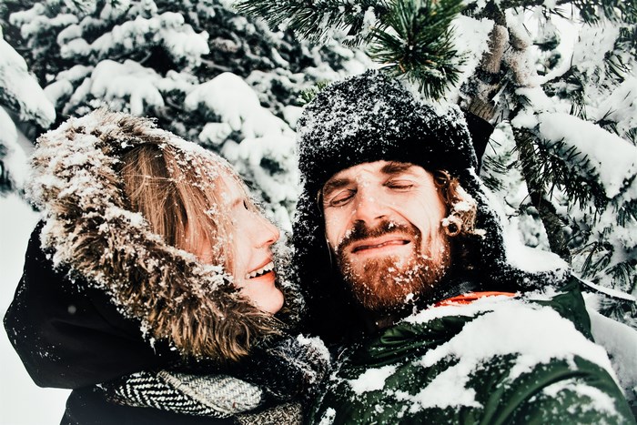 Couple covered in snow in a winter forest