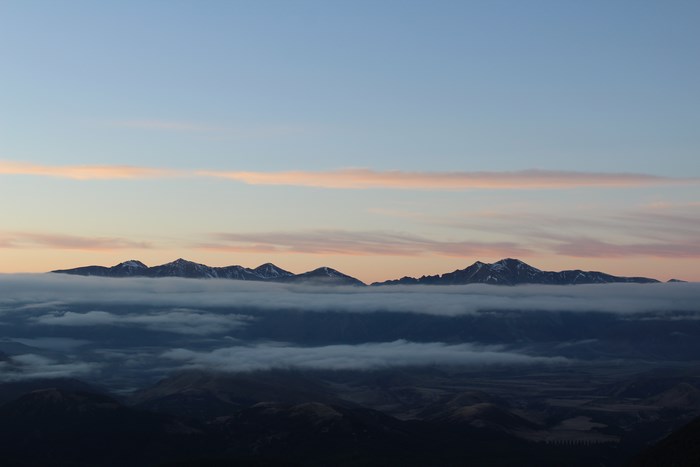 Mountains shrouded in fog at sunrise with pink clouds