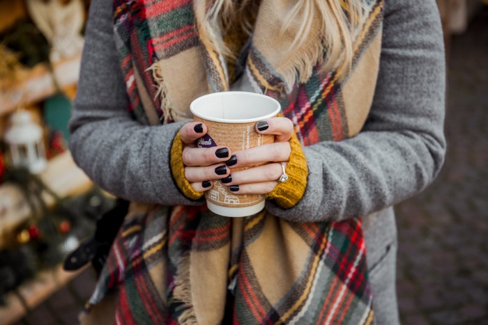 Woman holding a cup with a scarf and coat