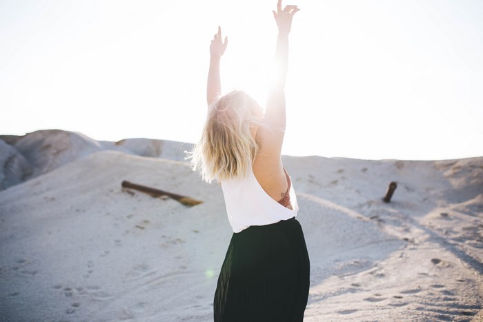 Woman with arms raised in a sandy landscape