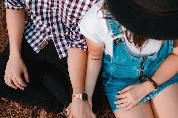 Couple holding hands with tattoos and watches