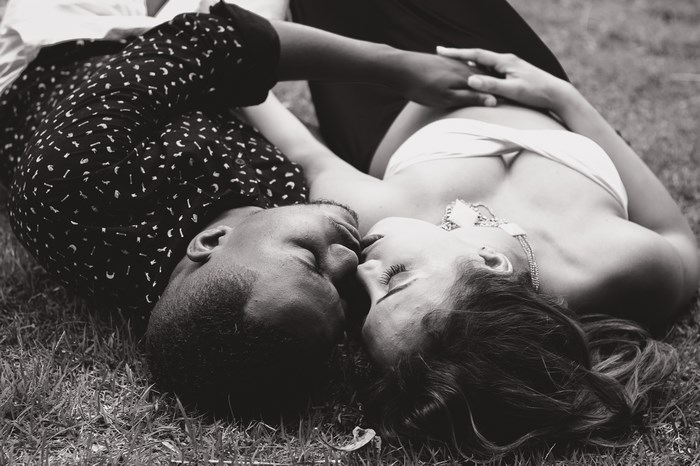 Couple lying down and kissing on grass
