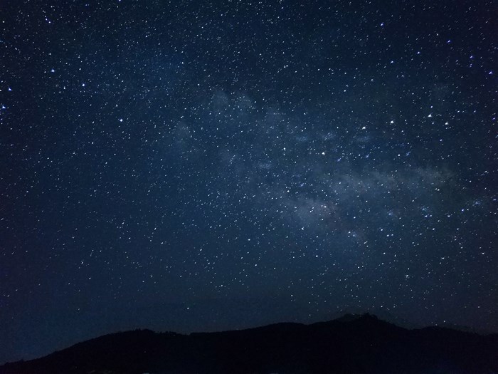 Starry night sky over a dark mountain silhouette