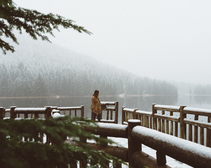 Woman on a snowy footbridge by a lake