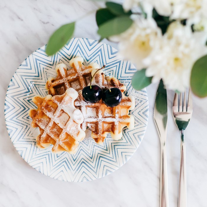 Waffles with cherries on a patterned plate