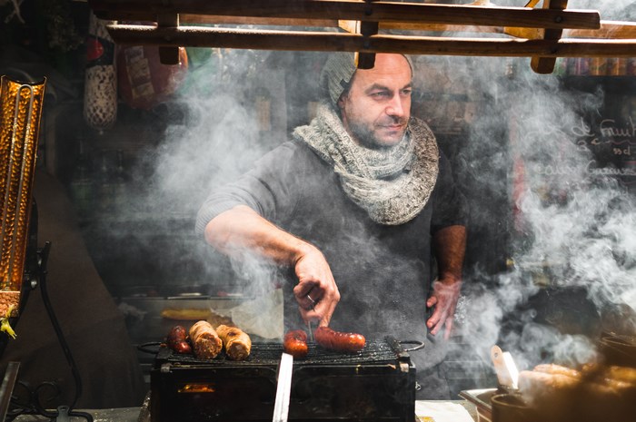 Man grilling sausages at a street food stall