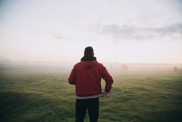 Man in red jacket standing in a foggy field