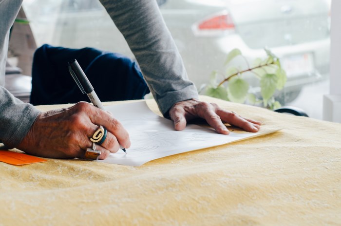 Elderly person drawing on paper with a pen