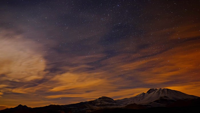 Starry night sky over snow-capped mountains