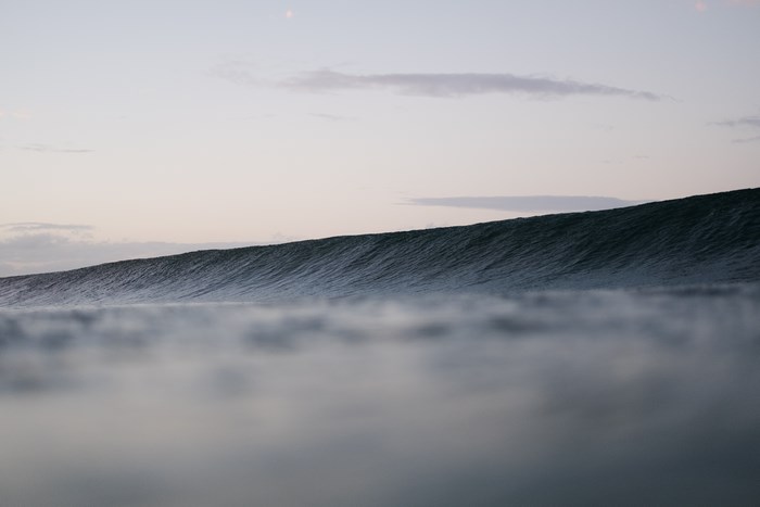 Ocean wave at dusk with clouds