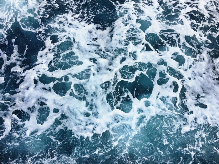 Churning blue ocean water with white foam