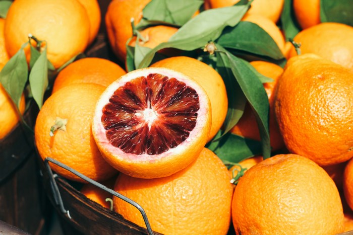 Blood orange cut in half with whole oranges