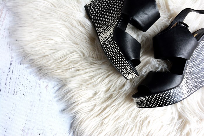 Black wedge sandals on a white shag rug