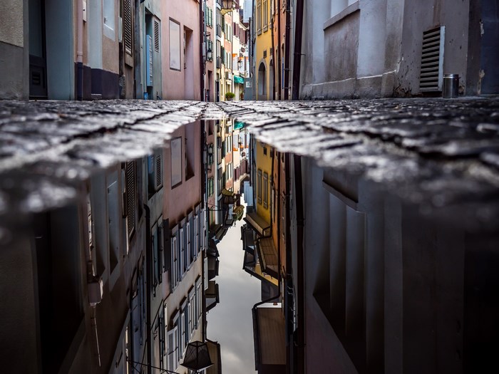 Reflection of a cobblestone alley in a puddle in Switzerland