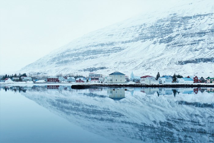Snowy mountain village reflected in calm water