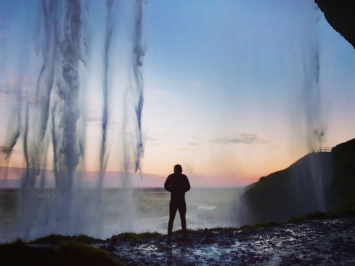 Man standing in front of Seljalandsfoss waterfall in Iceland