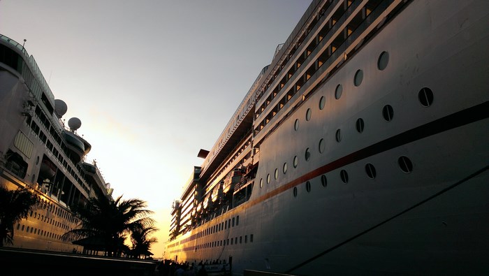 Two cruise ships docked at sunset with palm trees