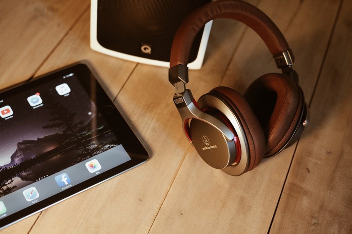 Audio-Technica headphones and tablet on a wooden desk