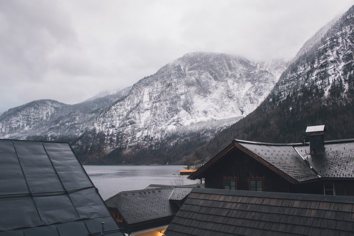 Snow-covered mountains and lake with rooftops in foreground