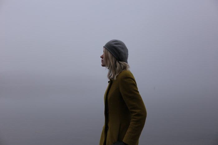 Woman in yellow coat and hat in fog