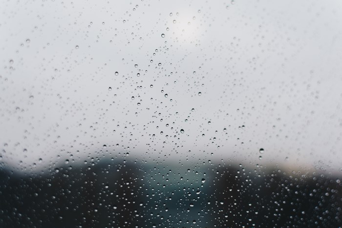 Raindrops on a window pane with blurred background