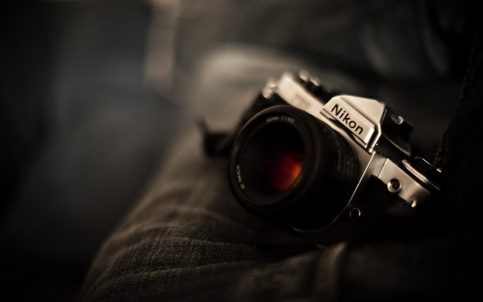 Nikon camera with 50mm lens on jeans
